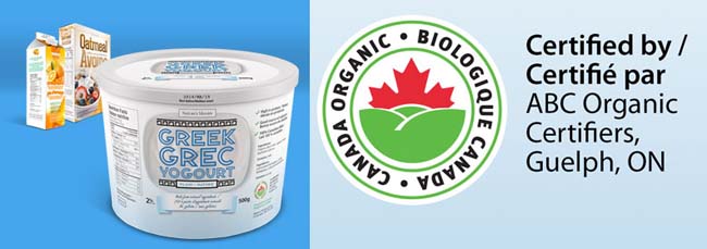 A 500 grams container of Greek yogourt at the front with a carton of orange juice and a box of oatmeal cereal in the far back left corner. To the right is a closer view of the Canada organic logo and a statement identifying the certification body on the Greek yogourt label.