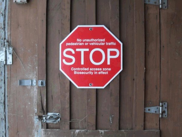 A photo of a biosecurity sign on a gate. Description follows.